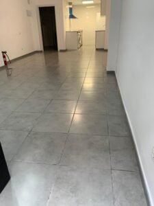 Interior reformado, con suelo gris y cocina blanca al fondo