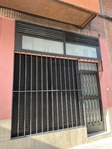 Fachada del espacio reformado, con carpintería oscura, ventanal y puerta de acceso